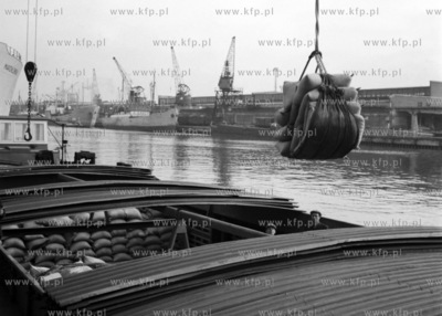 Wyładunek worków ze zbożem z barki na statek w porcie...