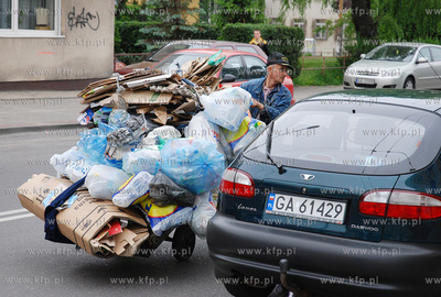 Mezczyzna ciagnacy wozek z makulatura na skrzyzowaniu...