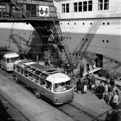 Pasażerowie wychodzą ze statku do stojącego obok...