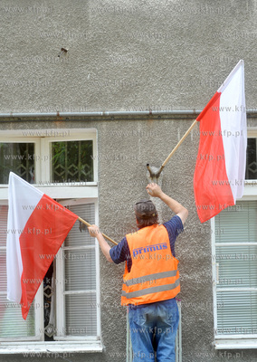 Zawieszanie flagi panstwowej na budynku kamienicy przy...