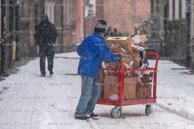Zimowy Gdańsk. Nz. Czlowiek pchajacy wózek z makulaturą...