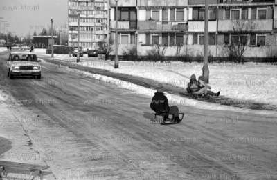 Dzieci zjezdzaja na sankach na osiedlowa uliczke w...