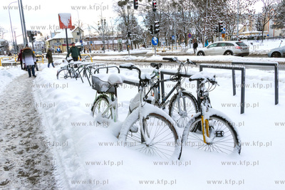 Zaśnieżone rowery stojące przy przystanku komunikacji...
