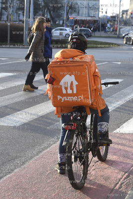 Kurier serwisu pyszne.pl stoi przed przejściem dla...
