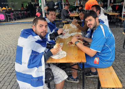 Greccy kibice siedza na lawie w ogrodku gastronomicznym...