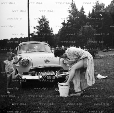 Kobieta myje samochód marki opel i przy okazji swoje...