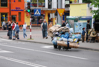 Mezczyzna ciagnacy wozek z makulatura na skrzyzowaniu...