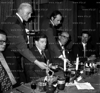 Kelnerzy obsluguja gosci w restauracji .Nz pierwwszy...