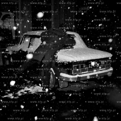 Odśnieżanie samochodu stojącego przed Domem Prasy...