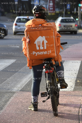 Kurier serwisu pyszne.pl stoi przed przejściem dla...