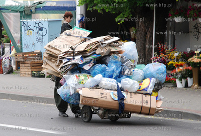 Mezczyzna ciagnacy wozek z makulatura na skrzyzowaniu...