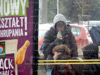 Młodzież spożywa produkt z szaszetki na przystanku...