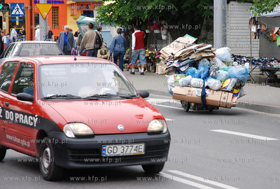 Mezczyzna ciagnacy wozek z makulatura na skrzyzowaniu...