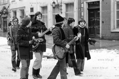 Mlodziez spiwajac i grajac na gitarach przechodza ulica...