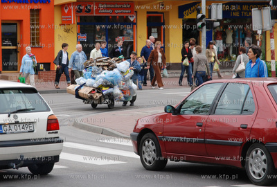 Mezczyzna ciagnacy wozek z makulatura na skrzyzowaniu...