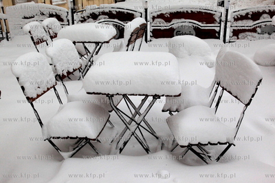 Zasniezone stoliki i krzesla w odgodkach restauracyjnych...