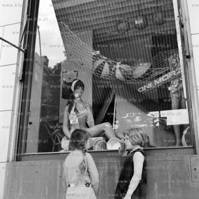 Dzieci stoją przed witryną Powszechnego Domu Towarowego...