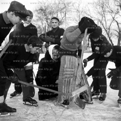 Mlodziez pomaga przy ubieraniu w hokejowy stroj bramkarski....