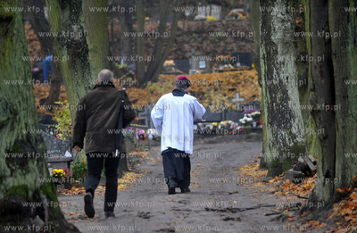 Ksiądz idzie alejką po pogrzebie na cmentarzu św....