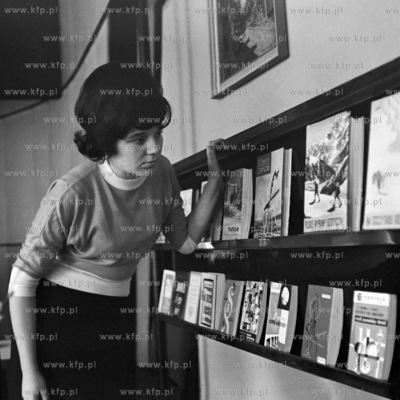 Kobieta przygląda się książkom ułożonym na księgarnianej...