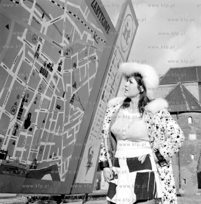 Dziewczyna w futrze pozuje do zdjec przed planem Gdanska...