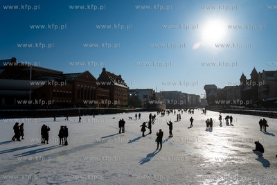 Spacerowicze na skutej lodem Motławie w Gdańsku....