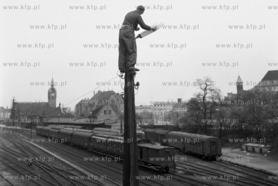 Pracownik PKP konserwuje slup oswietleniowy przy torowisku...
