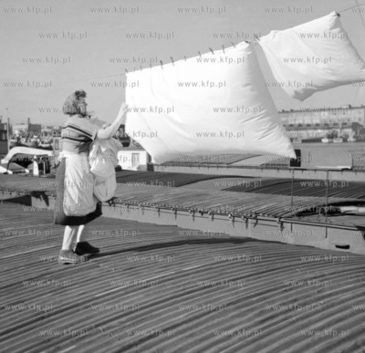Kobieta suszy koldry na barce zacumowanej przy nabrzezu...