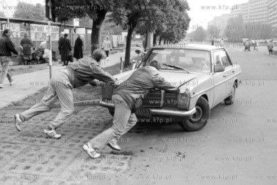 Mezczyzni pchaja samochod marki mercedes na ul. Czerwony...