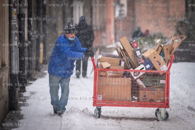 Zimowy Gdańsk. Nz. Czlowiek pchajacy wózek z makulaturą...