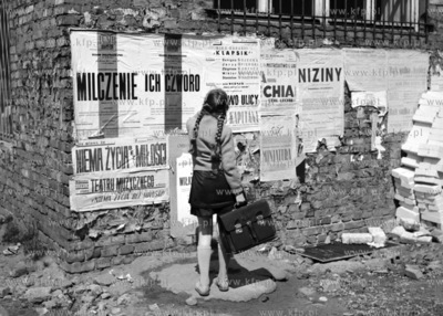 Dziewczynka przygląda się wiszącym na cegalnej ścianie...