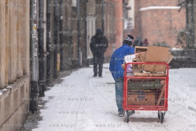 Zimowy Gdańsk. Nz. Czlowiek pchajacy wózek z makulaturą...