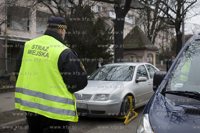 Strażnicy miejscy zakładają blokady na koła żle...