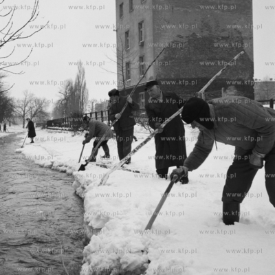 Pracownicy służb miejskich krusza lód  na kanale...
