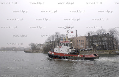 Przeplywajacy przez Motlawe holownik na tle budynków...